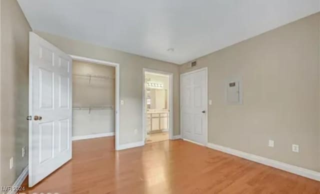 unfurnished bedroom with hardwood / wood-style flooring, a spacious closet, electric panel, and a closet