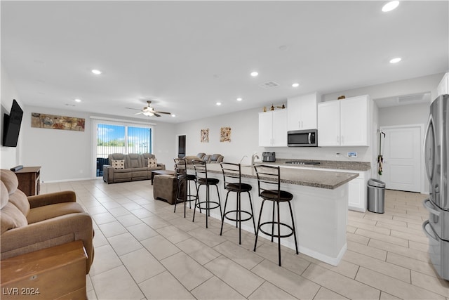 kitchen featuring a kitchen bar, white cabinetry, stainless steel appliances, and stone counters