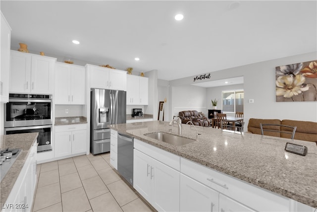 kitchen featuring light stone countertops, stainless steel appliances, white cabinetry, and sink