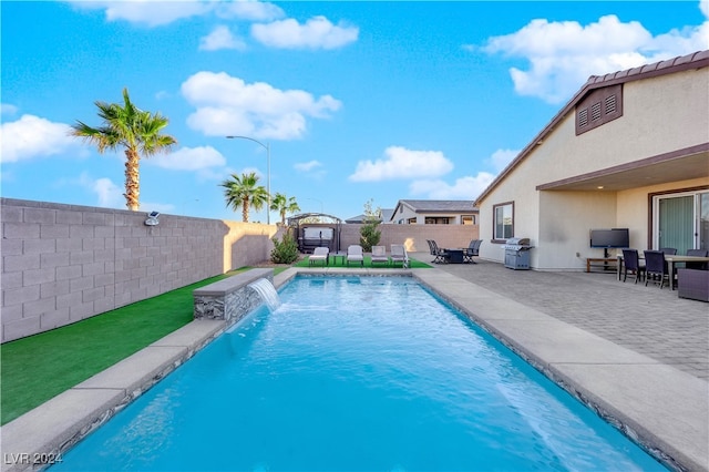 view of swimming pool featuring grilling area, pool water feature, and a patio area