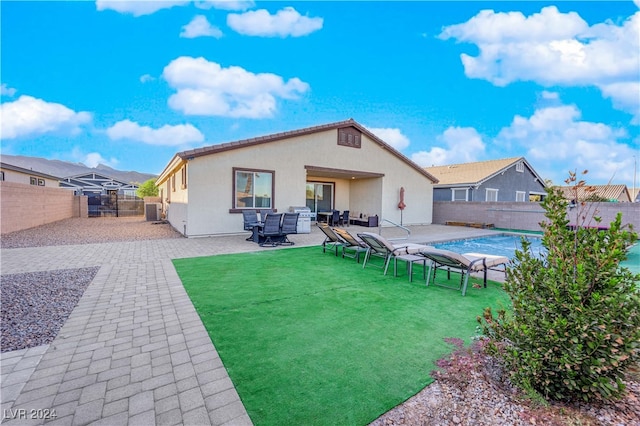 rear view of house with a patio area, a yard, and a fenced in pool