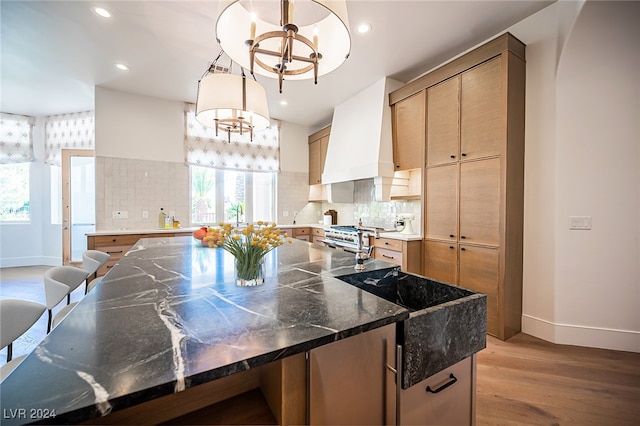 kitchen featuring light hardwood / wood-style flooring, a healthy amount of sunlight, dark stone counters, and pendant lighting