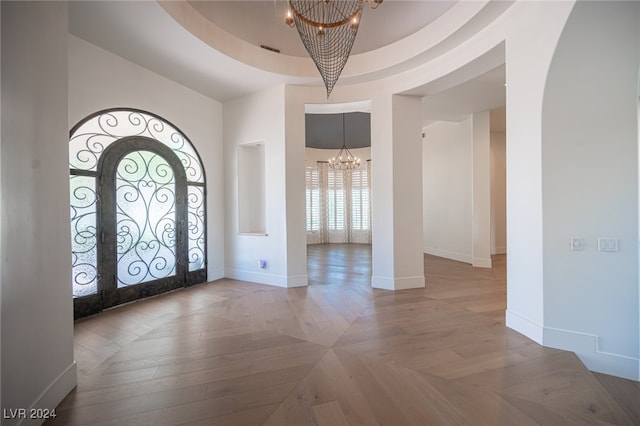 entrance foyer with french doors, a raised ceiling, and a chandelier