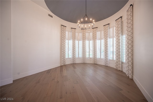 empty room featuring a chandelier and wood-type flooring