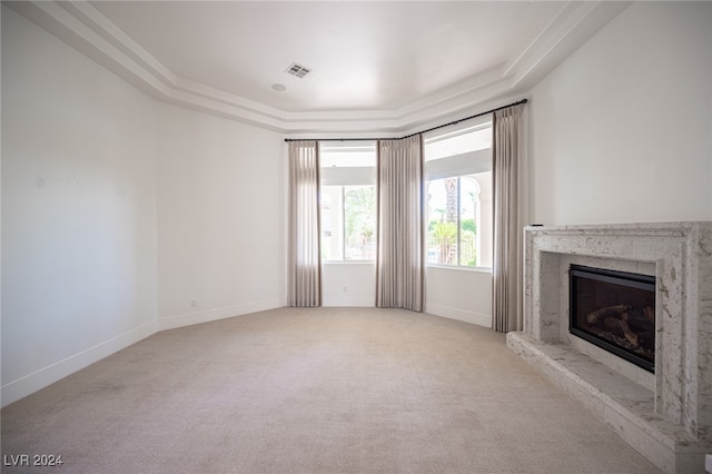 unfurnished living room featuring crown molding, light colored carpet, and a raised ceiling