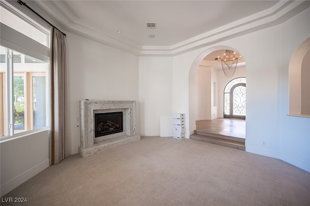 unfurnished living room featuring light carpet and a raised ceiling