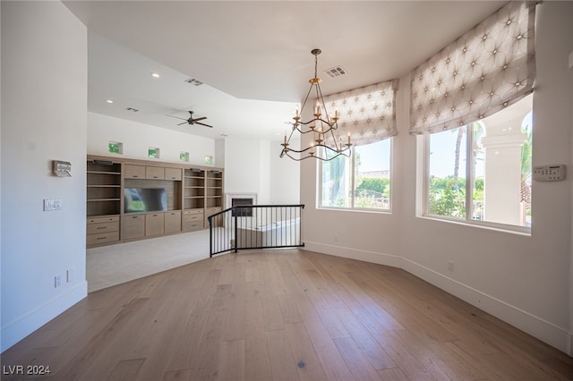 unfurnished living room featuring light hardwood / wood-style flooring and ceiling fan with notable chandelier