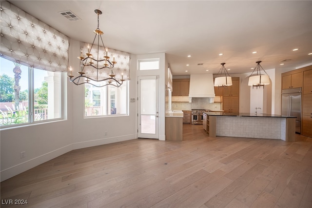 kitchen featuring tasteful backsplash, hanging light fixtures, light hardwood / wood-style flooring, custom range hood, and premium appliances