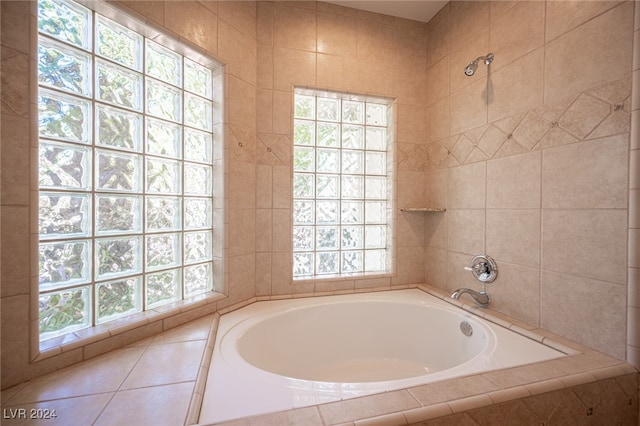 bathroom with tiled tub and a healthy amount of sunlight