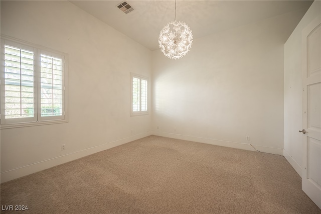 unfurnished room with carpet and a chandelier