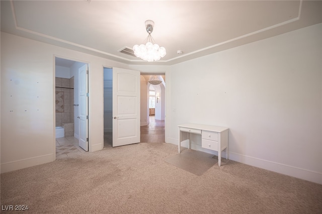 unfurnished bedroom featuring an inviting chandelier, ensuite bath, and light colored carpet