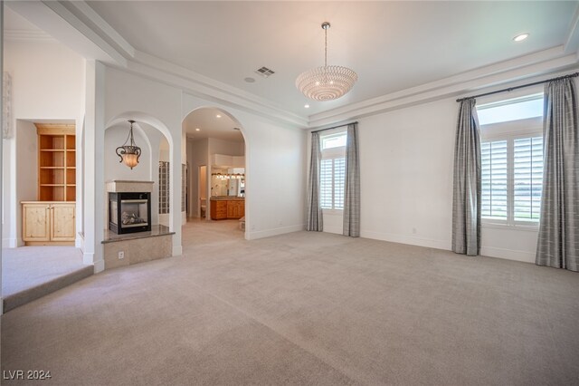 unfurnished living room with light carpet, ornamental molding, and a wealth of natural light