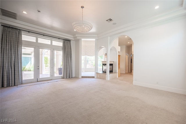 unfurnished living room with light carpet, a multi sided fireplace, a chandelier, crown molding, and french doors