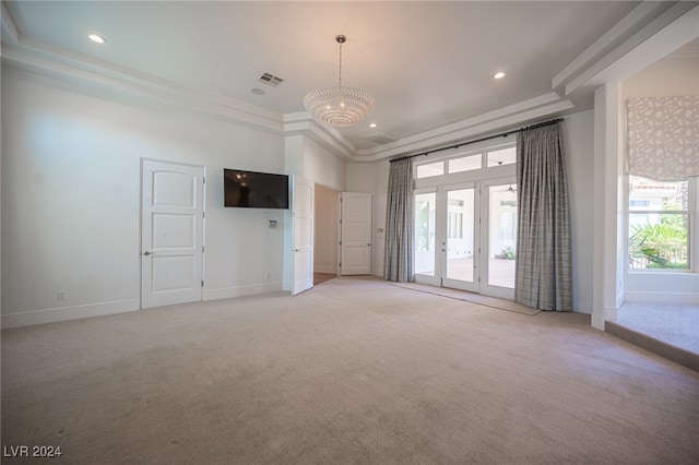 spare room with a tray ceiling, crown molding, light colored carpet, and a chandelier