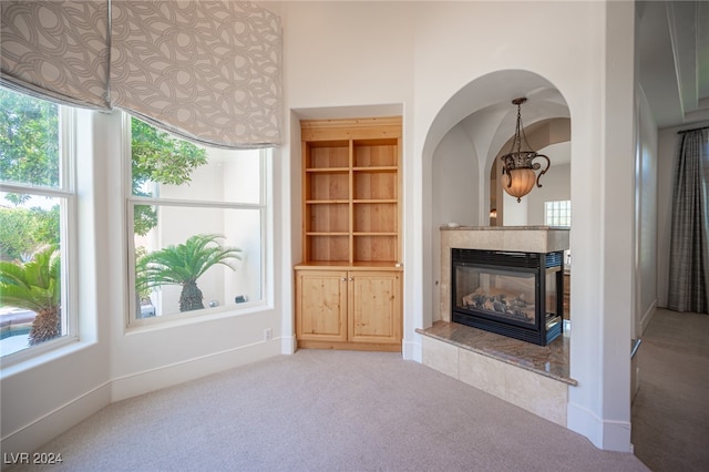 unfurnished living room featuring a fireplace, carpet flooring, and plenty of natural light