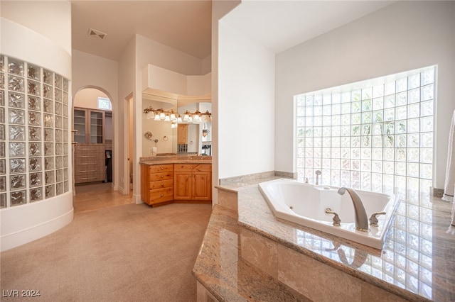 bathroom with vanity and tiled tub