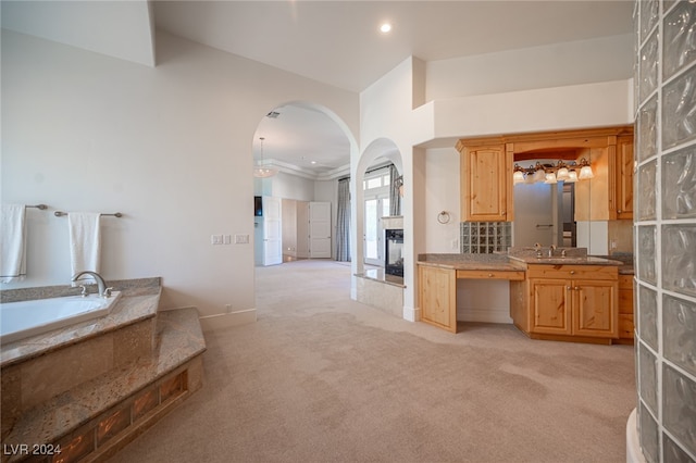 kitchen with a multi sided fireplace, ornamental molding, light colored carpet, and sink