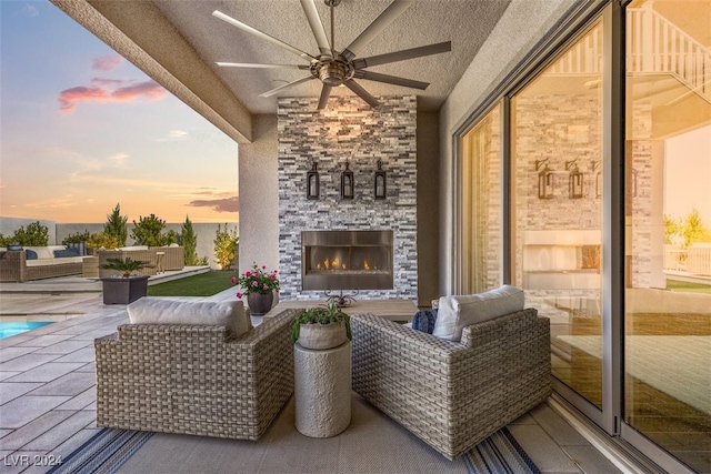 patio terrace at dusk featuring an outdoor living space with a fireplace and ceiling fan