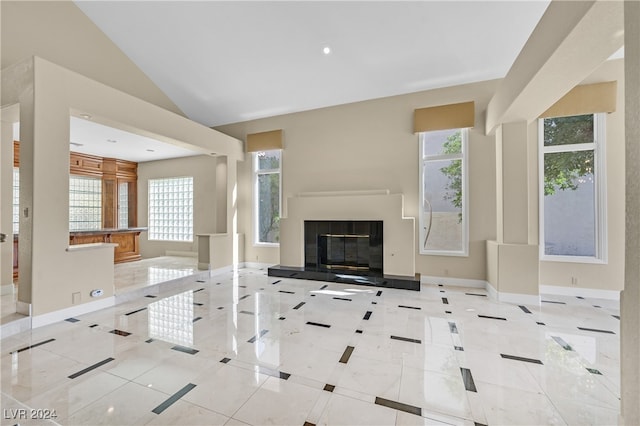 unfurnished living room with vaulted ceiling, light tile patterned floors, and a healthy amount of sunlight