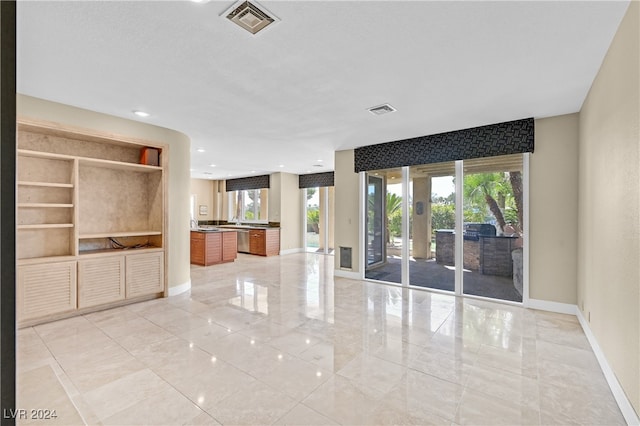 unfurnished living room with french doors, plenty of natural light, and built in shelves