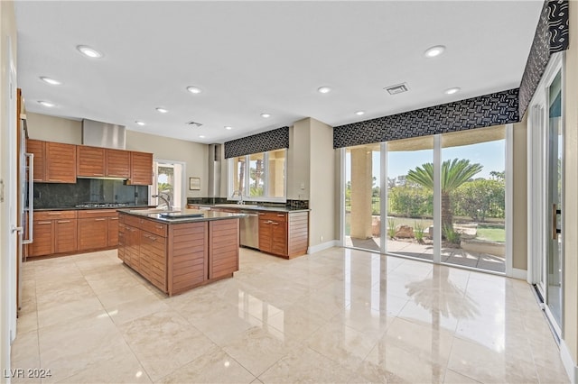 kitchen featuring a healthy amount of sunlight, decorative backsplash, dishwasher, and a kitchen island with sink