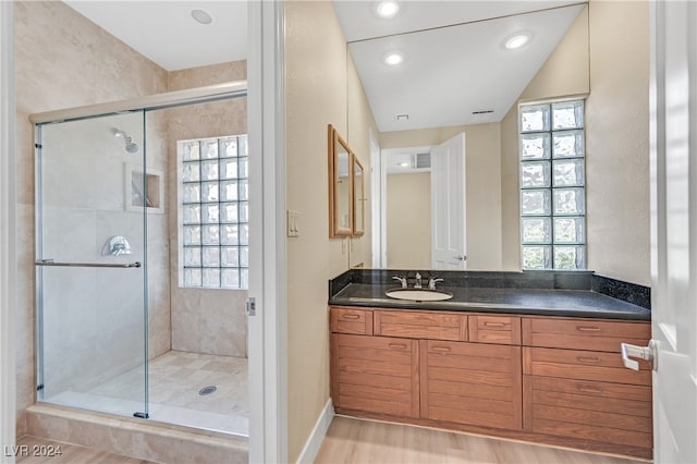 bathroom with wood-type flooring, vanity, and an enclosed shower