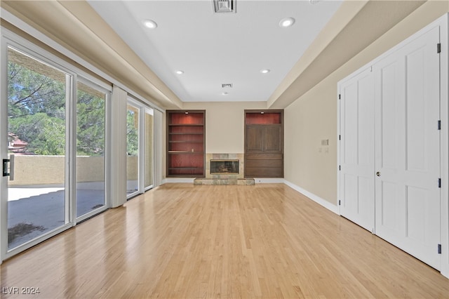 unfurnished living room with a stone fireplace and light hardwood / wood-style floors