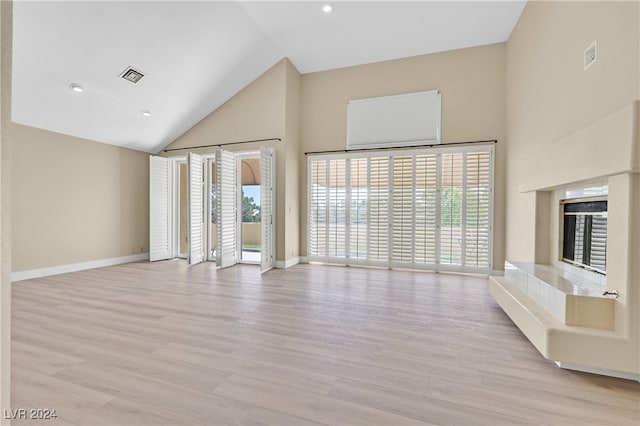 unfurnished living room with light hardwood / wood-style floors and high vaulted ceiling