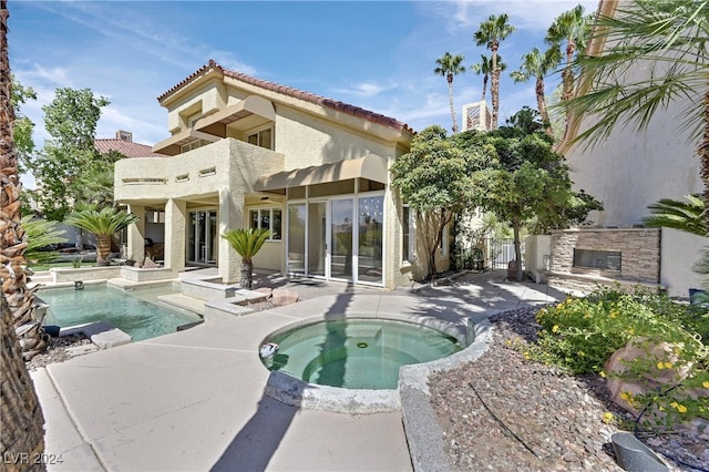 back of property with a pool with hot tub and a patio area