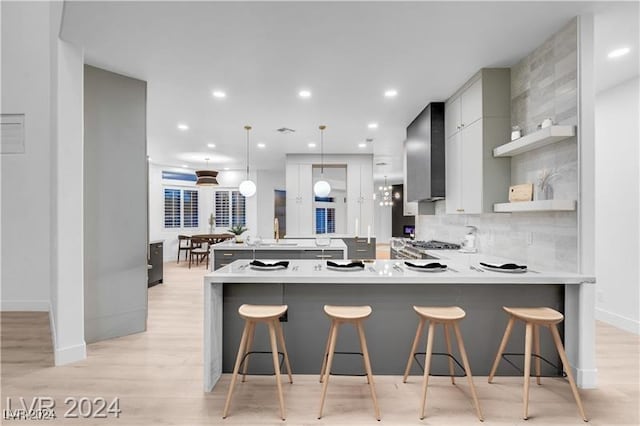 kitchen with gray cabinets, decorative light fixtures, kitchen peninsula, and a breakfast bar