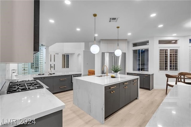 kitchen featuring appliances with stainless steel finishes, pendant lighting, gray cabinets, a center island, and sink