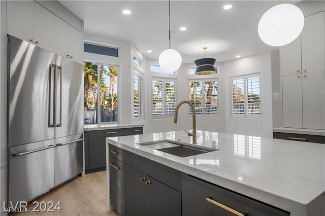 kitchen with a healthy amount of sunlight, hanging light fixtures, high end refrigerator, and sink