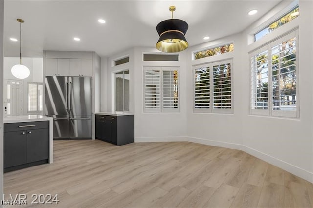 kitchen with white cabinets, light hardwood / wood-style flooring, high quality fridge, and decorative light fixtures