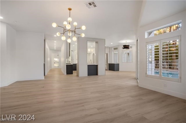 unfurnished living room featuring a notable chandelier and light hardwood / wood-style floors