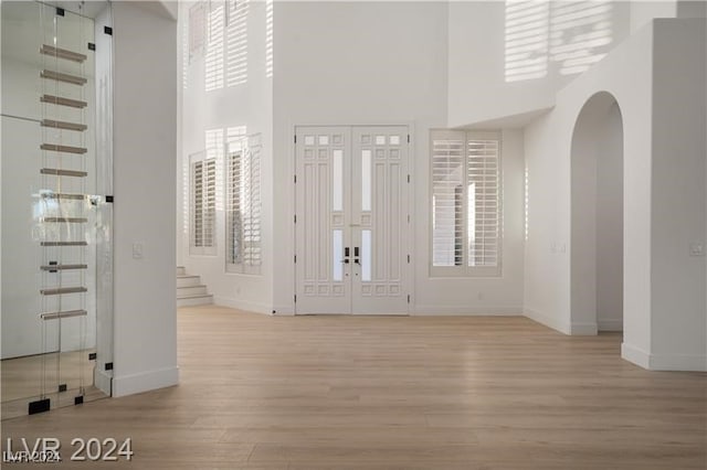 foyer with light wood-type flooring and a towering ceiling