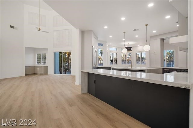 kitchen with ceiling fan, pendant lighting, light hardwood / wood-style flooring, and plenty of natural light