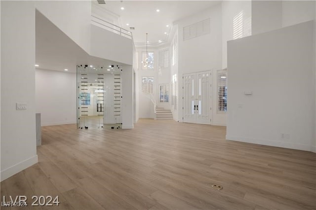 unfurnished living room with a towering ceiling and wood-type flooring