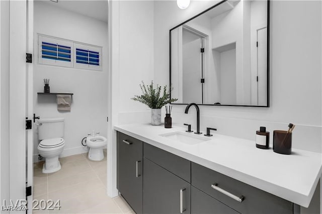 bathroom with vanity, toilet, a bidet, and tile patterned floors