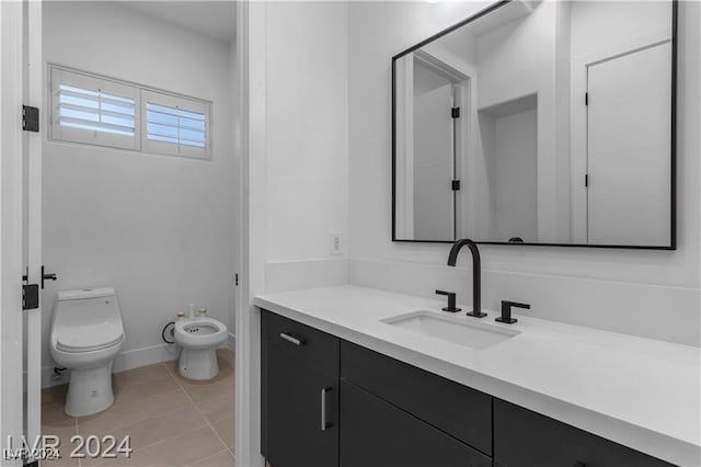 bathroom with a bidet, vanity, toilet, and tile patterned floors