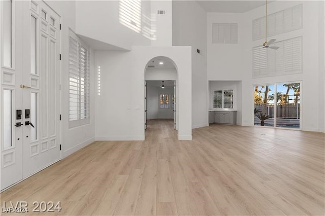 entryway featuring light hardwood / wood-style flooring, a towering ceiling, and ceiling fan