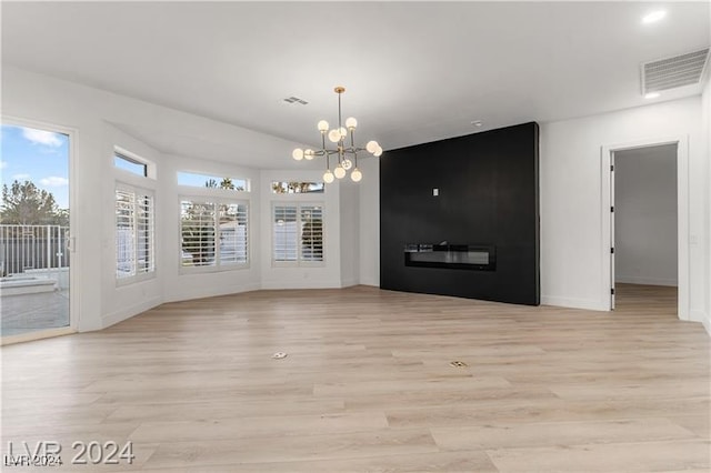 unfurnished living room with an inviting chandelier and light hardwood / wood-style floors