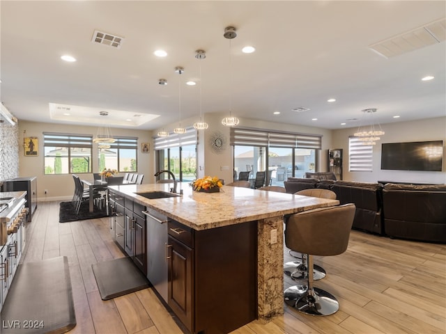 kitchen featuring decorative light fixtures, sink, a wealth of natural light, and light hardwood / wood-style flooring