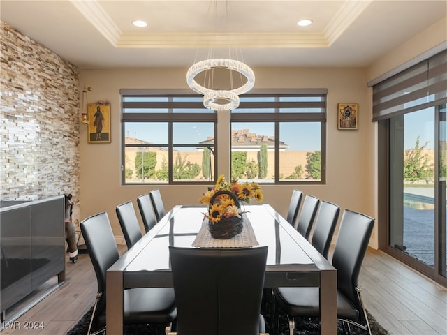 dining room featuring an inviting chandelier, light wood-type flooring, ornamental molding, and a tray ceiling