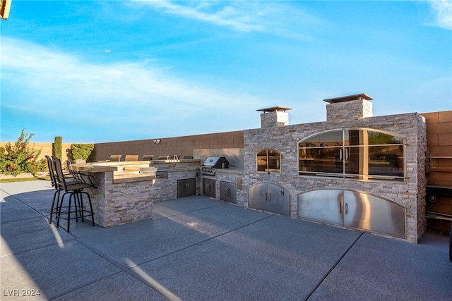 view of patio with exterior kitchen, a grill, and a bar