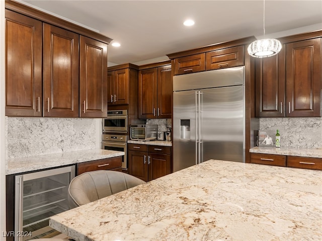 kitchen with pendant lighting, a breakfast bar, backsplash, wine cooler, and stainless steel appliances