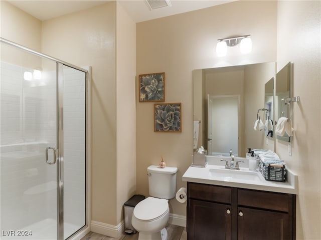 bathroom featuring hardwood / wood-style floors, vanity, toilet, and an enclosed shower