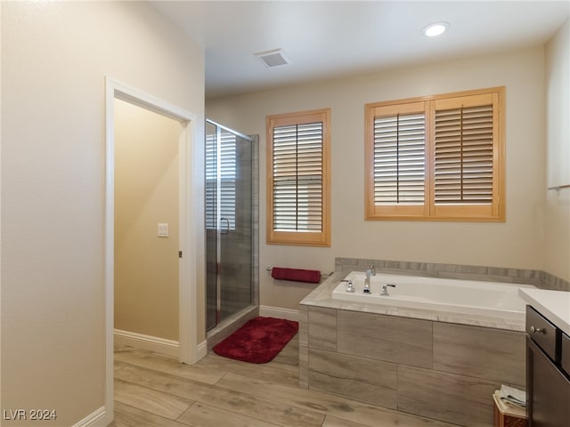 bathroom with plus walk in shower, wood-type flooring, and vanity