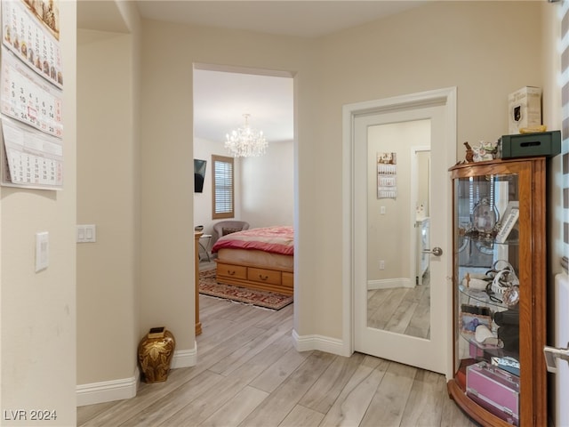 hallway featuring a chandelier and light hardwood / wood-style flooring