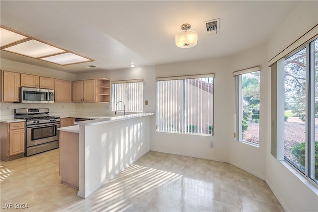 kitchen featuring light brown cabinetry, kitchen peninsula, appliances with stainless steel finishes, and sink