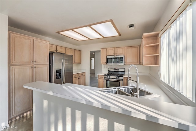 kitchen featuring kitchen peninsula, light brown cabinets, sink, and stainless steel appliances